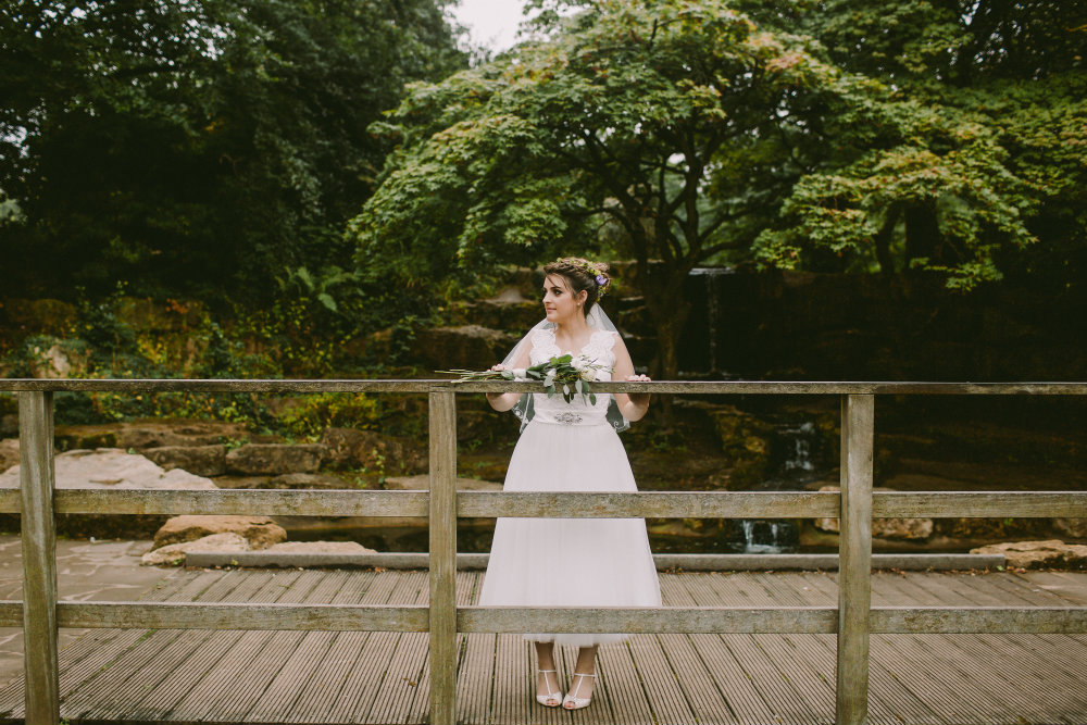 Bride stood on bridge over pond