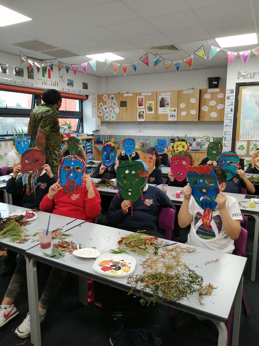 School children holding brightly coloured masks they have made to their faces