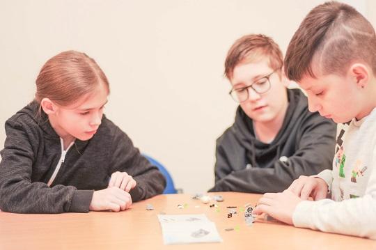 Three children sat around a table talking