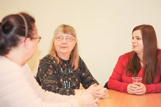 Three adults sat talking