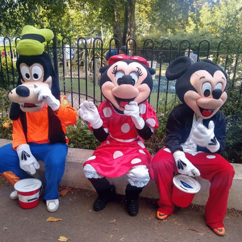 Goofy Minnie and Micky sat on a bench with charity buckets
