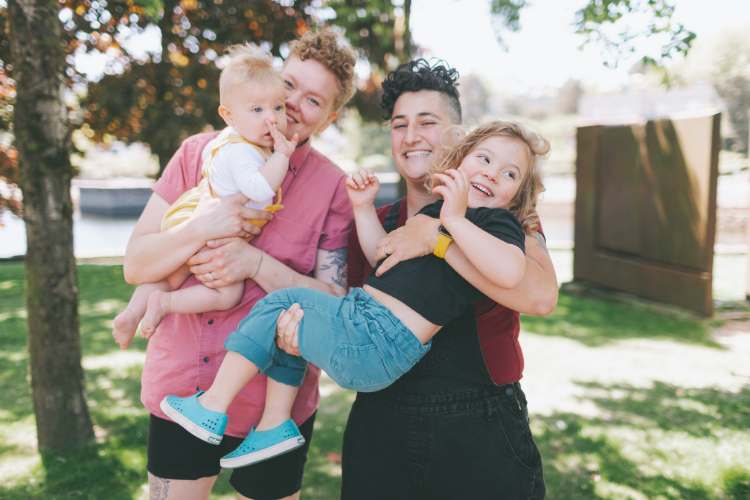two adult females hugging two young children