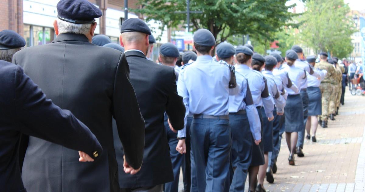 Service men and women marching through a town.