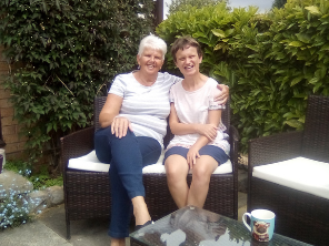 Two smiling women sat together in a garden.