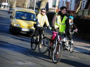 Adults cycling on a suburban road.