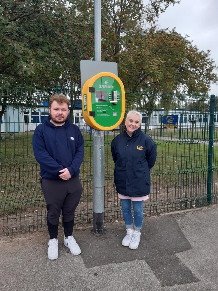 Councillor Mills and School headteacher stood nect to the new defibrillator