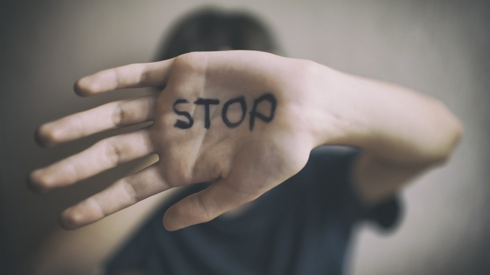 Someone holding their hand sideways to the camera, with the word STOP written on it.