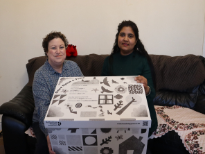 Cllr Victoria Cusworth, Cabinet Member for Children and Young Peoples Services, sat on a sofa beside mum Jaspreet Kaur. Both women are holding a baby pack.