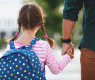 Girl wearing blue backpack, holding hands with father.