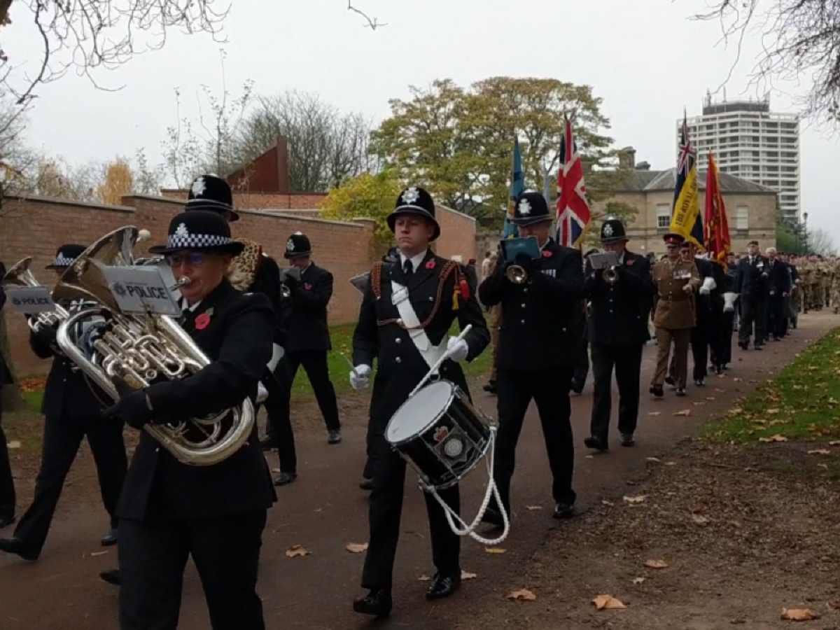 Police band marching through Clifton Park while playing brass instruments and drums at the 2021 Rotherham Remembers event