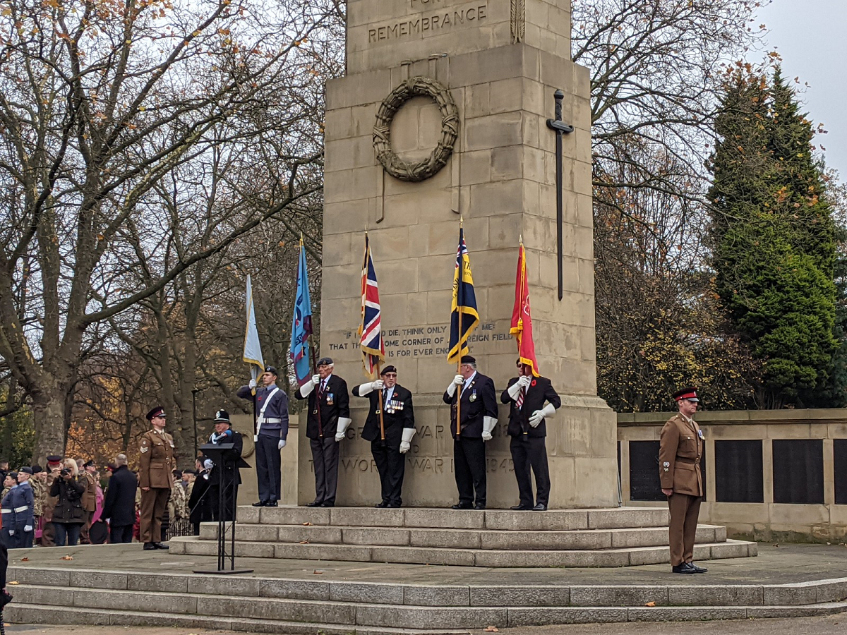 Serving and retired military personnel holding ceremonial flags in front of Clifton Park cenotaph at the 2021 Rotherham Remembers event