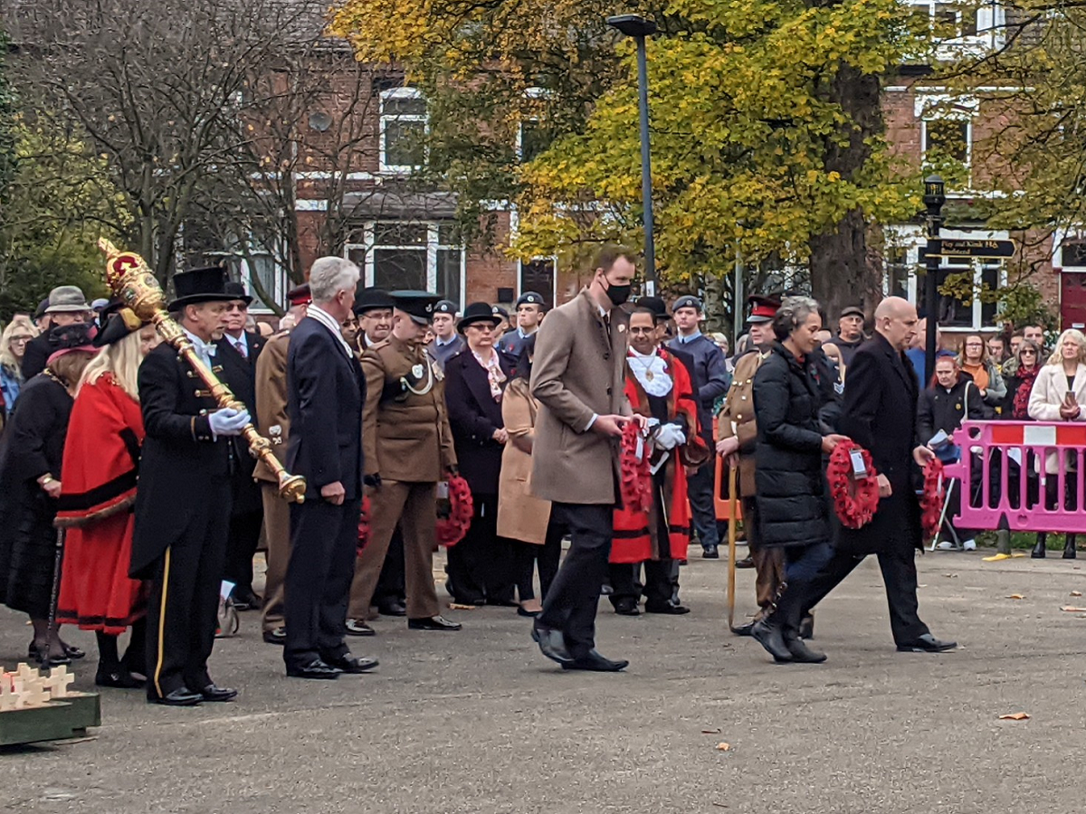 Leader of Rotherham Council, Councillor Chris Read, and local MPs Sarah Champion and John Healey, approach Clifton Park cenotaph holding poppy wreaths at 2021 Rotherham Remembers event