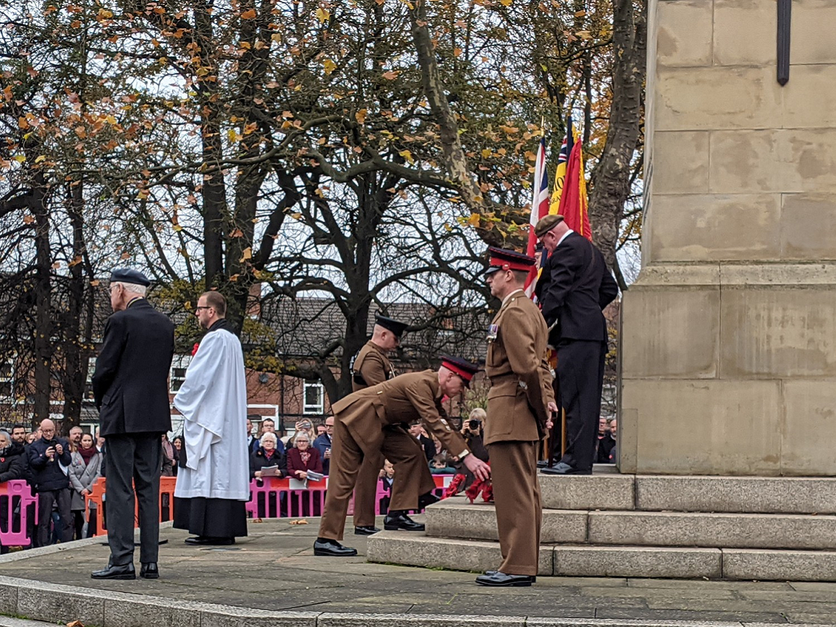 Soldiers in brown dress uniform placing poppy wreaths on the Clifton Park cenotaph during the 2021 Rotherham Remembers event