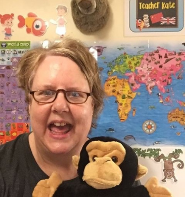 A woman smiling and holding a toy monkey.