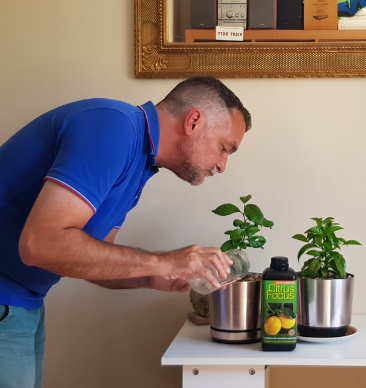 A man watering some plants in his house.