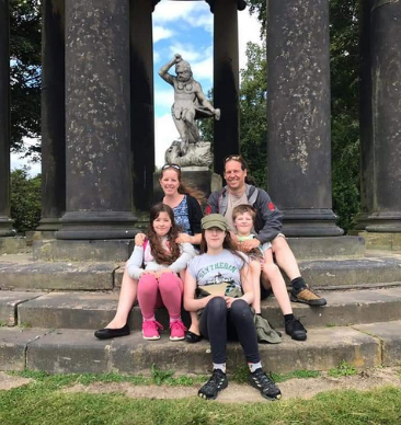 A family sat on some steps in front of an ancient monument.