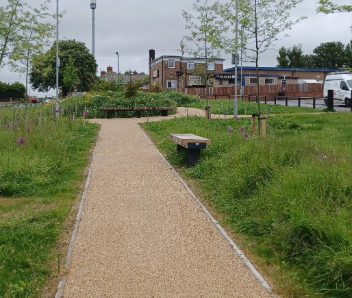  A light beige path with greenery either side.