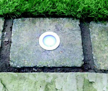 A spotlight shown in the floor with grey stone slabs around it