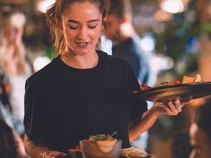 Woman in a restaurant serving food to customers