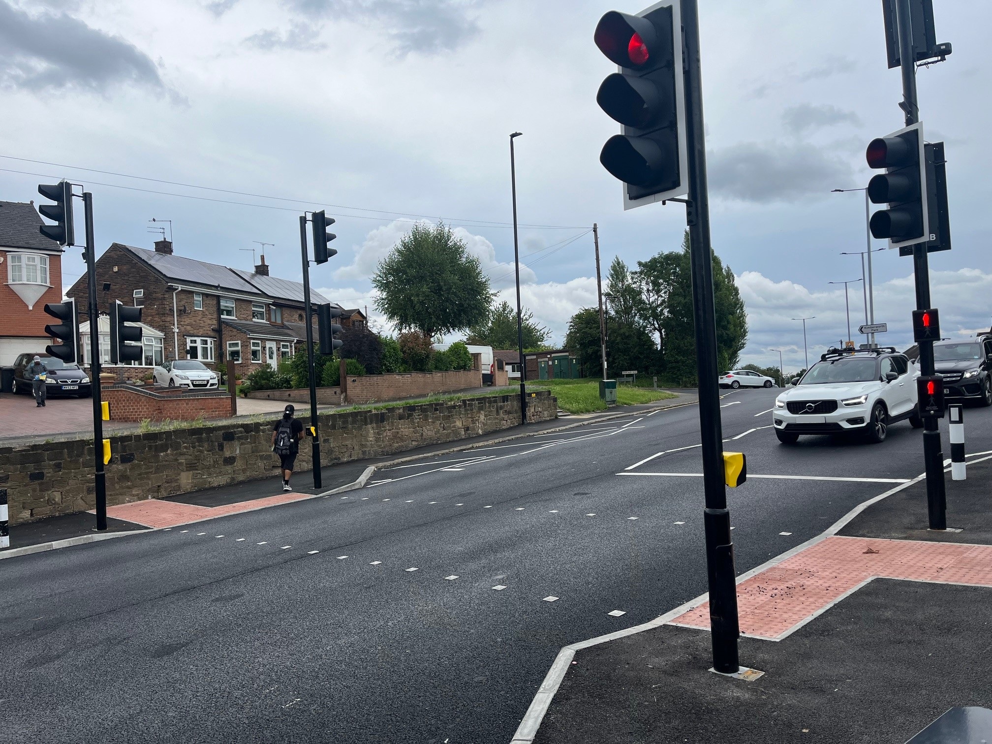 A photograph of a crossing on Upper Wortley road and a car is stopped at a red light.