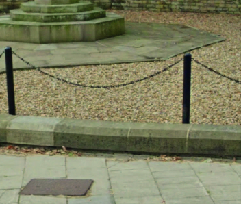 A picture of orange gravel around the Cenotaph with a black railing around it.