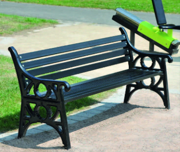 A black metal bench on a beige path is shown.