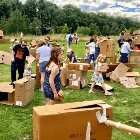 A field filled with people and cardboard boxes.