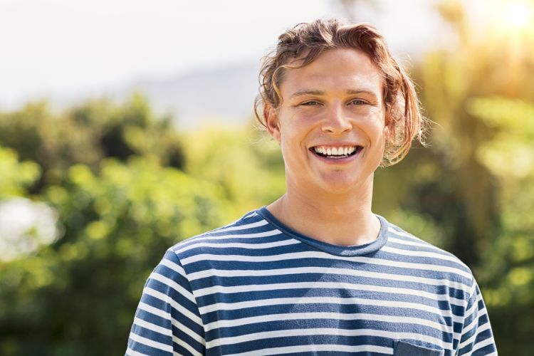 male with a blue and white striped shirt smiling at the camera