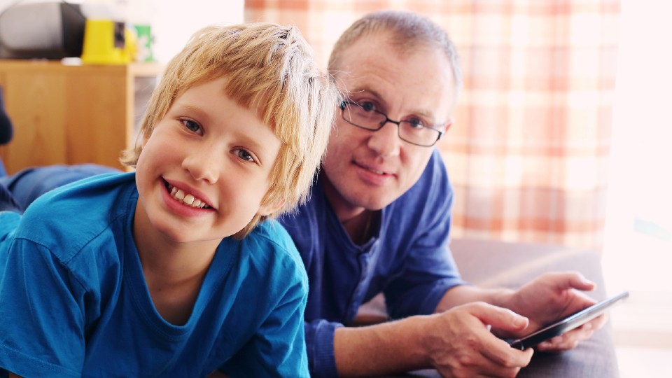 Boy and man playing on tablet device