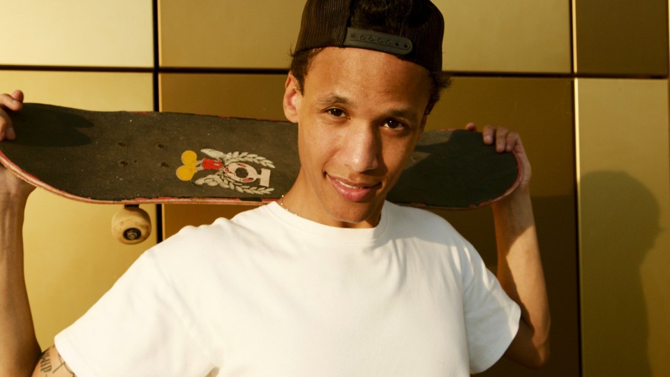 Boy holding skateboard behind his head