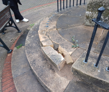 A broken step around the Cenotaph with a black railing with a section missing.