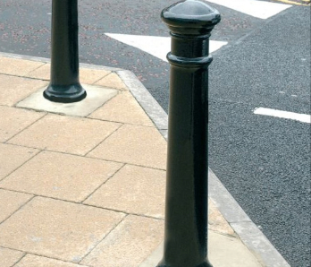 Black bollards at the edge of path to stop cars parking on the path.