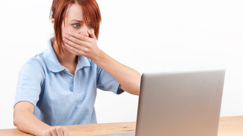 Girl using laptop, looking shocked