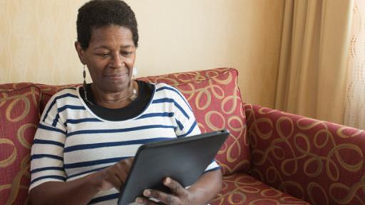 Woman using tablet device at home on sofa
