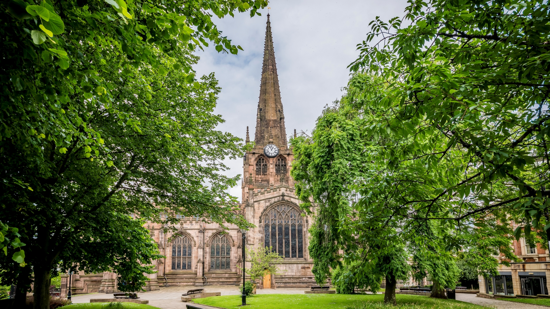 Rotherham Minster and garden lined with trees.