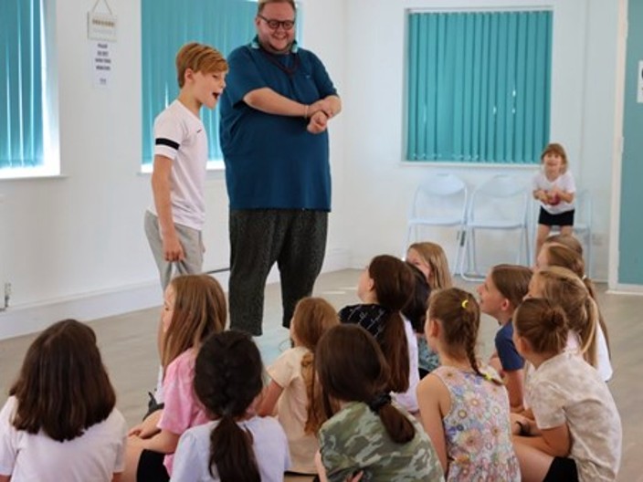 Dance class with group sat listening to group leader and young person