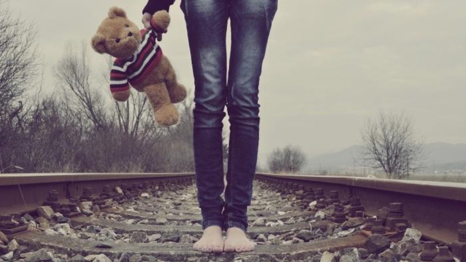 Person walking barefoot along railway tracks