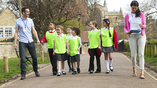 photo of two adults and several children walking along a footpath